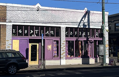 A white brick storefront painted with EGYPTIAN COFFEE in block letters between purple window frames.