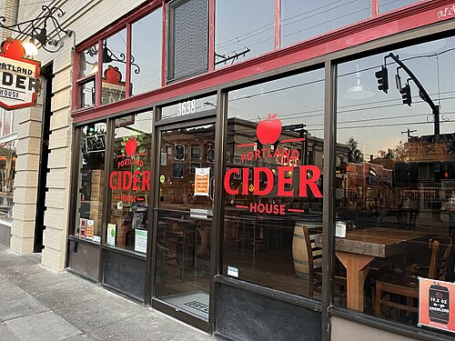 A dark storefront with red lettering on the glass and the boulevard reflected in the window.