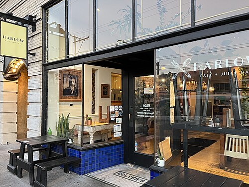 A brick storefront with black-framed windows and a blue tile base, a mosaic tile reading COLYER'S set into the sidewalk at the entrance.