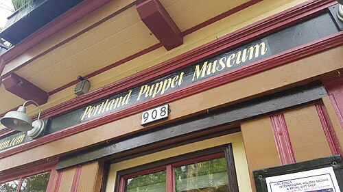 The Portland Puppet Museum's yellow and maroon storefront on SE Umatilla Street, its number 908 painted over the door.