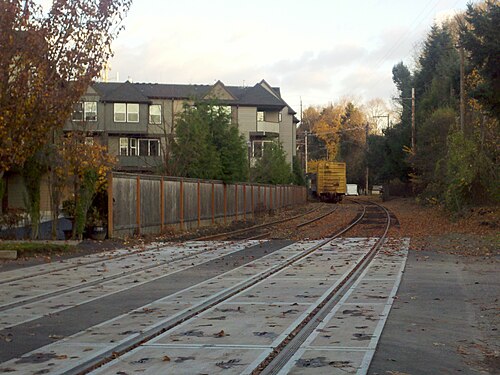 The rail line through Sellwood, tracks curving past a wood fence with newer town houses behind it.
