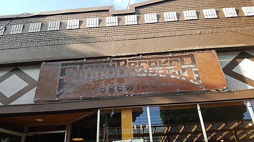 StormBreaker Brewing's corroded steel sign against a brick storefront patterned in a diamond design.