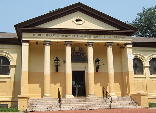 A single storey classical library building with a columned portico and pedimented roofline, THE FREE LIBRARY OF PHILADELPHIA MC PHERSON SQUARE BRANCH lettered across the front.