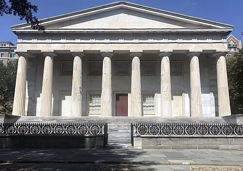 The marble Greek Revival front of the Second Bank of the United States, eight fluted columns under a pediment behind an iron fence.