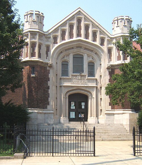 The Free Library's Richmond branch on Almond Street, a Tudor Revival front with castellated corner towers behind a black iron fence.