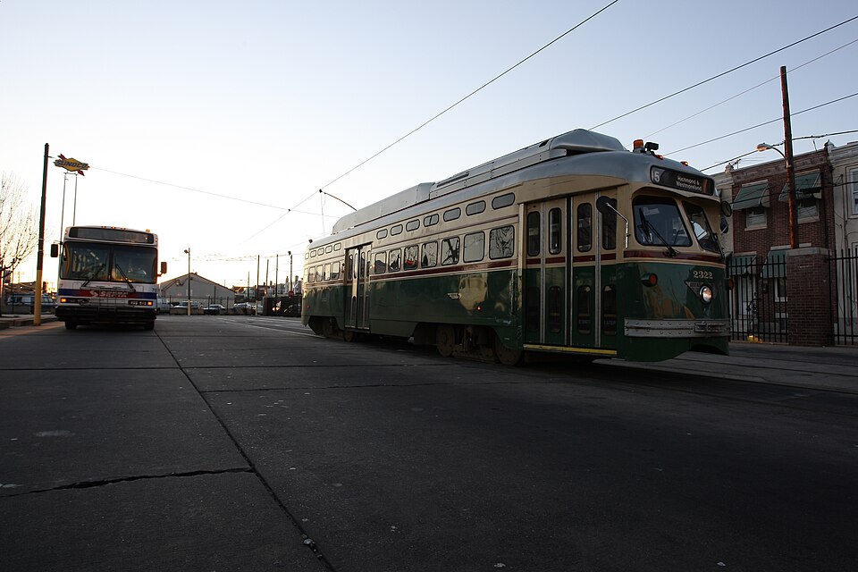 The Route 15 trolley loop at Richmond and Westmoreland Streets, brick rowhouses behind it and a SEPTA bus alongside. A representative Port Richmond rowhouse corner, not Ontario Street itself.