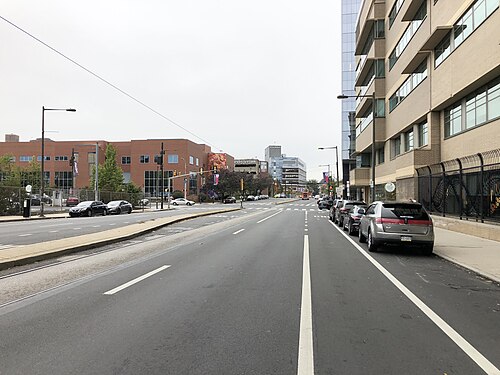 38th Street southwest of Market, a divided avenue with trolley tracks in the asphalt and hospital towers behind a red brick medical building.
