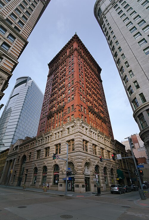 The First National Bank building at Fourth Avenue and Wood Street, a narrow red brick and terra cotta tower over a rusticated granite base, seen from directly below.