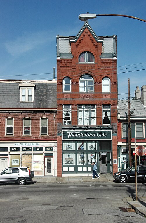 A narrow four storey red brick building on Butler Street with decorative gables, the Thunderbird Cafe sign over the ground floor.