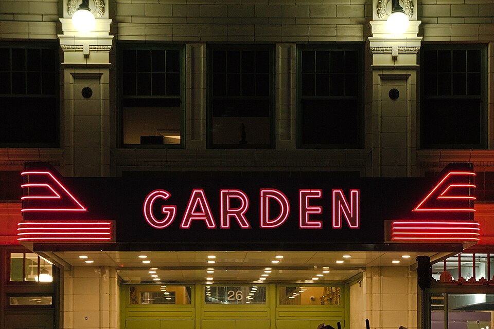 The Garden Theater's illuminated red neon marquee reading Garden at night, with the building's upper floor windows visible above it.