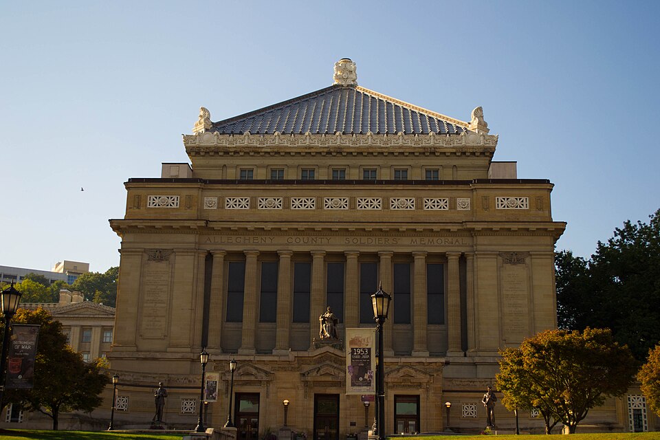 A different Oakland civic hall with a full colonnade of stone columns and a red tile roof on a lawn, the kind of grand colonnade the Mellon Institute has, not the building itself.