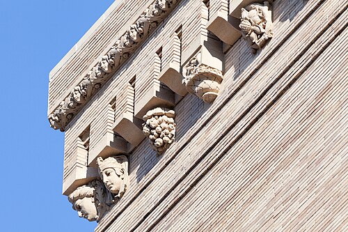 A close view of the Pittsburgh Mercantile Building's corner cornice, carved stone faces and fruit clusters under the roofline.