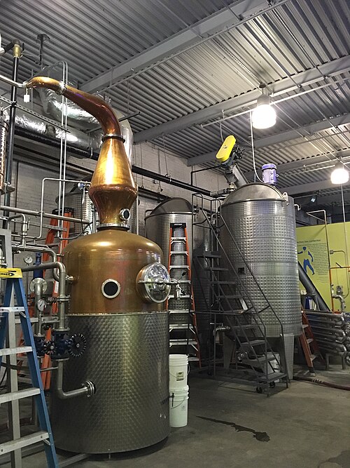 The copper still and steel fermentation tanks inside Wigle Whiskey's production floor, ladders and catwalks between them.