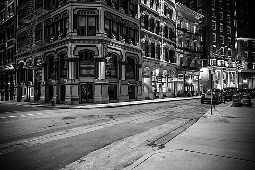 A stone office building on a Weybosset Street corner at night, arched ground floor windows, attorney and jewelry shop signs, and an empty street.