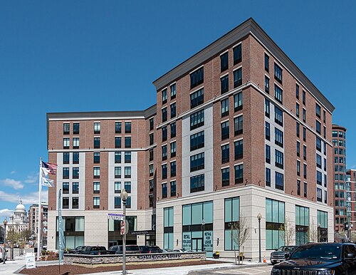 A brick and stone hotel building on a Financial District corner, the State House dome visible down the street past a flagpole.