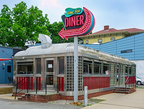 A chrome and red diner with a neon arrow sign on a pole, on Westminster Street.