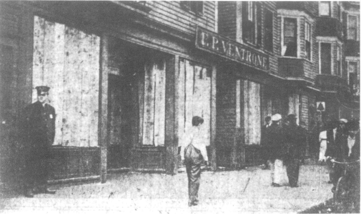 A 1914 photograph of a boarded wooden storefront at 240-244 Atwells Avenue, painted E. P. Ventrone signage above, onlookers on the sidewalk. Kept as a dated historical view, not a picture of the avenue as it stands today.