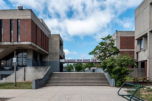 A modern concrete high school campus on Westminster Street, concrete stairs and an entrance sign above the doors.