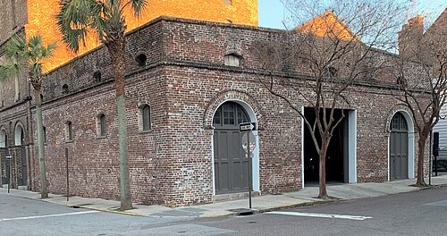 A single storey red brick commercial building on a corner, with an arched dark grey double door and a brick parapet against the sky.