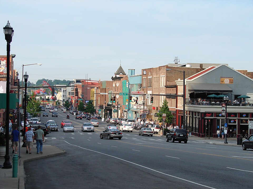 Broadway looking east from above Fifth Avenue, the street running downhill toward the Cumberland with low brick buildings and projecting signs along both sides.