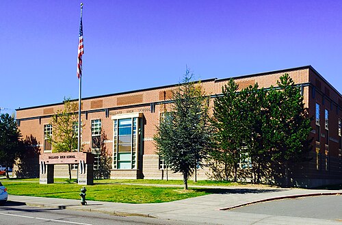 Ballard High School's brick main facade, tall windows, a flagpole and lawn out front.