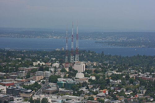 Capitol Hill's rooftops seen from downtown, three radio towers on the ridge and open water beyond.