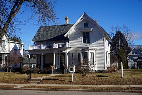 The Beulah Brinton House, a two storey white clapboard house with a wraparound porch, a bay window and a gabled roof, house number 2590 over the door.