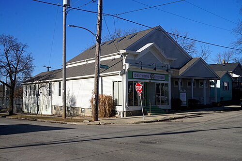 Delaware House, a one storey white sided corner building with green trim at a residential intersection.
