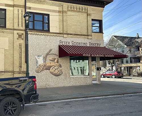 The Peter Sciortino Bakery corner at Humboldt Avenue, a tan brick two storey building with a tiled bread and wheat mosaic worked into the ground floor wall beside a dark red awning.