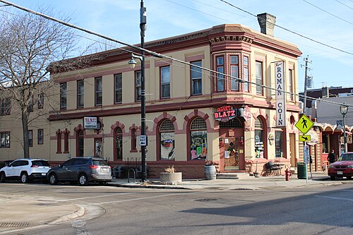 Regano's Roman Coin, a turreted corner building in cream brick with red trim, arched second floor bay windows, and a lit BLATZ sign over the door.