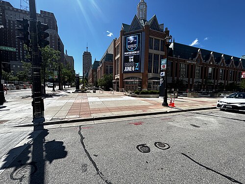 The Baird Center's brick front with a gabled roofline and a large digital display, a wide paved plaza in front under a clear sky.