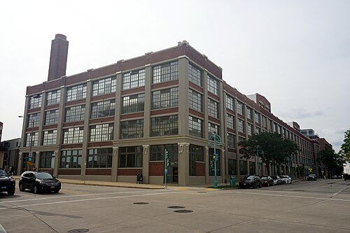 A two storey glass and steel market hall with its name spelled out in block letters across the roofline, an elevated freeway ramp passing overhead.