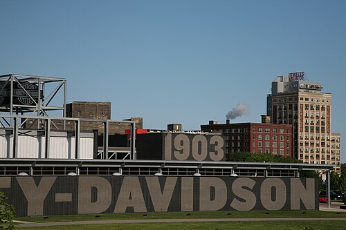 The Harley-Davidson Museum's black wall lettered 1903 and HARLEY-DAVIDSON, the historic Teweles Seed Co. tower rising behind it.